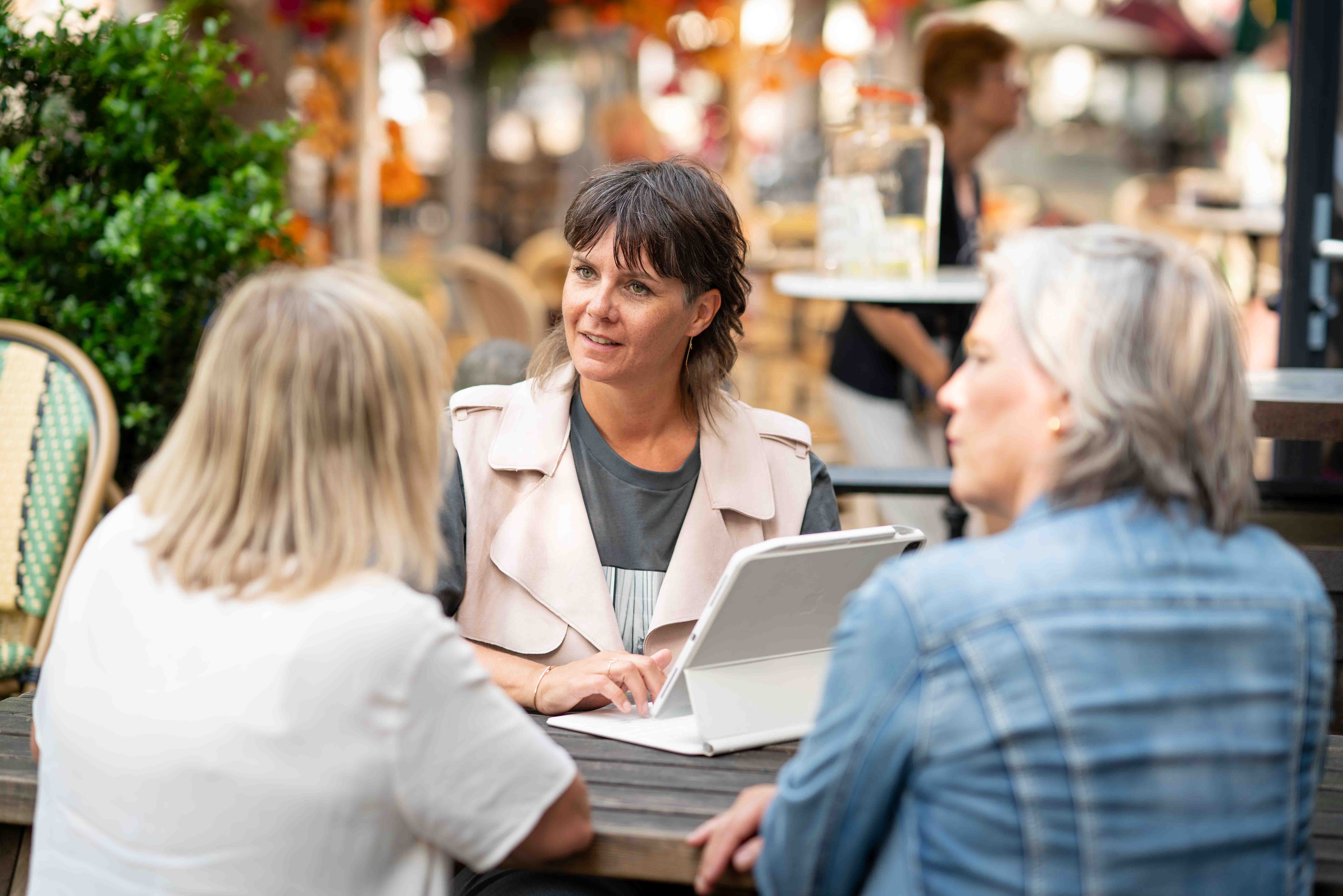 Saskia achter een iPad in overleg met twee collega's